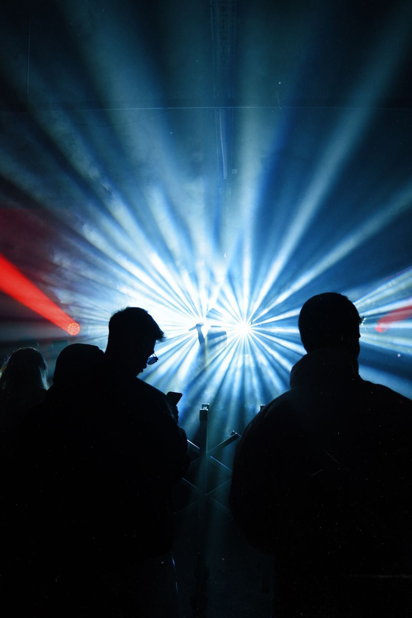 Concert crowd silhouetted against bright stage beams